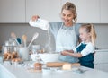 Mother helping her daughter sift flour into a bowl. Happy mother and daughter baking in the kitchen.Caucasian little Royalty Free Stock Photo