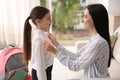 Mother helping her little daughter to get ready for school indoors Royalty Free Stock Photo
