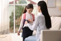 Mother helping her little daughter to get ready for school indoors Royalty Free Stock Photo