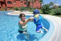 Madre ayudar lo joven hijo en nadar y saltar en soleado 