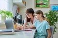 Mother helping preteen daughter to study, looking at laptop at home Royalty Free Stock Photo