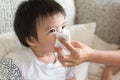 Mother helping to blow asian child`s nose with paper tissue. Sea Royalty Free Stock Photo