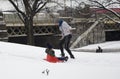 Mother helps her child ride sleigh in snow in Bronx NY park