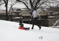 Mother helps her child ride sleigh in snow in Bronx NY park