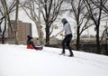 Mother helps her child ride sleigh in snow in Bronx NY park