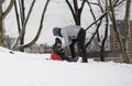 Mother helps her child ride sleigh in snow in Bronx NY park