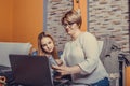 Mother helps her teenage daughter with homework, while are they together browsing internet on laptop Royalty Free Stock Photo