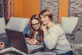 Mother helps her teenage daughter with homework, while they are together browsing internet on laptop and smartphone Royalty Free Stock Photo