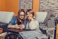 Mother helps her teenage daughter with homework, while they are together browsing internet on smartphone Royalty Free Stock Photo