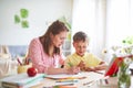 Mother helps son to do lessons. home schooling, home lessons. the tutor is engaged with the child, teaches to write and count