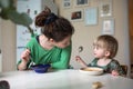 Mother with her baby eating soup in the bright kitchen at home Royalty Free Stock Photo