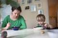 Mother with her baby eating soup in the bright kitchen at home Royalty Free Stock Photo