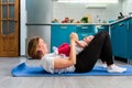A mother and her baby have fun doing fitness on a mat in the kitchen. The concept of home sports training with children Royalty Free Stock Photo