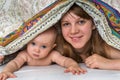 Mother and her baby playing and smiling under a blanket Royalty Free Stock Photo