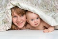 Mother and her baby playing and smiling under a blanket Royalty Free Stock Photo