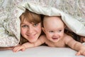 Mother and her baby playing and smiling under a blanket Royalty Free Stock Photo