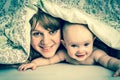 Mother and her baby playing and smiling under a blanket Royalty Free Stock Photo