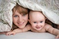 Mother and her baby playing and smiling under a blanket Royalty Free Stock Photo