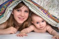 Mother and her baby playing and smiling under a blanket Royalty Free Stock Photo