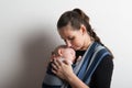 Mother with her baby son sleeping in sling. Studio shot. Royalty Free Stock Photo