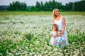 A mother with her blonde son and daughter in a field of daisies in bloom. Enjoy the fragrance of a bouquet of chamomile Royalty Free Stock Photo