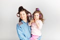 Mother and her child daughter with a lipstick. Portrait of a lovely little baby girl and her mum with curlers on their heads
