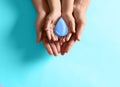 Mother and her child holding water drop on blue background, top view. Ecology protection Royalty Free Stock Photo