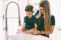 Mother with her child playing in kitchen sink