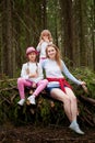 Mother and her child sister girls playing and having fun together on walk in forest outdoors. Happy loving family posing on nature Royalty Free Stock Photo