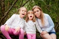 Mother and her child sister girls playing and having fun together on walk in forest outdoors. Happy loving family posing on nature Royalty Free Stock Photo