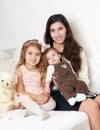 Mother with her children sit in the bed with teddy bear, happy family portrait Royalty Free Stock Photo