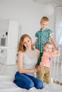 Mother and her children sitting on big bed in bedroom