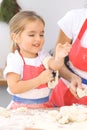 Mother and her cute daughter prepares the dough at wooden table. Homemade pastry for bread or pizza. Bakery background