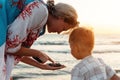 Mother and her cute little son collecting pebbles on shingle beach Royalty Free Stock Photo