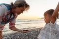 Mother and her cute little son collecting pebbles on shingle beach Royalty Free Stock Photo