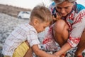 Mother and her cute little son collecting pebbles on shingle beach Royalty Free Stock Photo