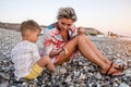 Mother and her cute little son collecting pebbles on shingle beach Royalty Free Stock Photo