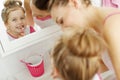 Mother and her daughter brush their teeth with toothbrushes in the bathroom at home. Mom and baby girl in home clothes. Royalty Free Stock Photo