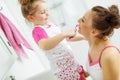 Mother and her daughter brush their teeth with toothbrushes in the bathroom at home. Mom and baby girl in home clothes. Royalty Free Stock Photo