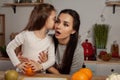 Mother and her daughter are doing a fruit cutting and having fun at the kitchen.