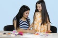 Mother and her daughter are drawing and making paper cutouts together.