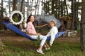 Mother and her daughter fooling around and sitting in hammock in the evening