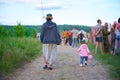 Mother and her daughter in handmade colorful caps going away by path