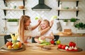 Mother with her daughter in kitchen preparing healthy food with fresh vegetables Royalty Free Stock Photo