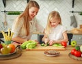 Mother with her daughter in kitchen preparing healthy food with fresh vegetables Royalty Free Stock Photo