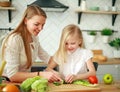 Mother with her daughter in kitchen preparing healthy food with fresh vegetables Royalty Free Stock Photo