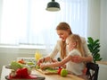 Mother with her daughter in kitchen preparing healthy food with fresh vegetables Royalty Free Stock Photo