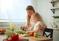 Mother with her daughter in kitchen preparing healthy food with fresh vegetables Royalty Free Stock Photo