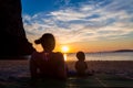 Mother with her daughter. Little baby girl of 9 months. Couple sitting back on a tropical beach, watching and enjoy the sunset. Royalty Free Stock Photo