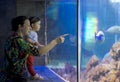 Mother with Her Daughter Are Looking in Aquarium with the Fishes Royalty Free Stock Photo